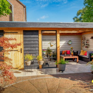 Veranda met kleine berging in de tuin met veel kleurrijke bloemen en planten