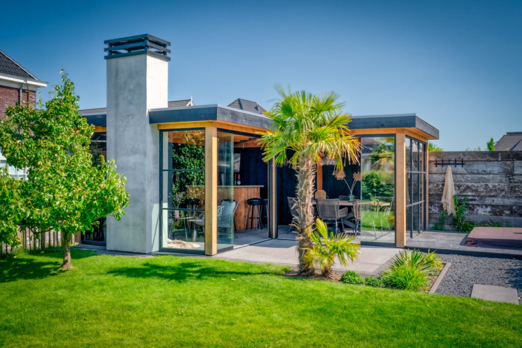 Modern tuinhuis met glazen schuifwand en grote buitenkachel