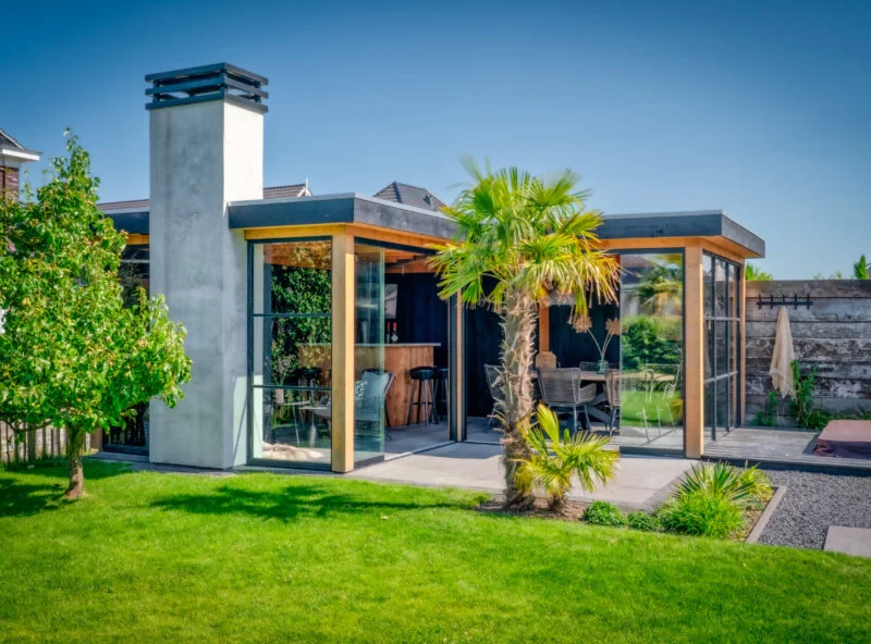 Modern tuinhuis met glazen schuifwand en grote buitenkachel