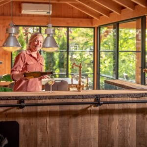 Overkapping met buitenkeuken en vrouw die een wijnglas inschenkt